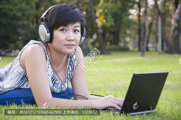 美麗的亞洲女人在公園聽音樂