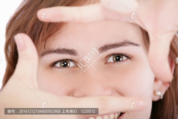 漂亮的成年女子透過她的手框架看。