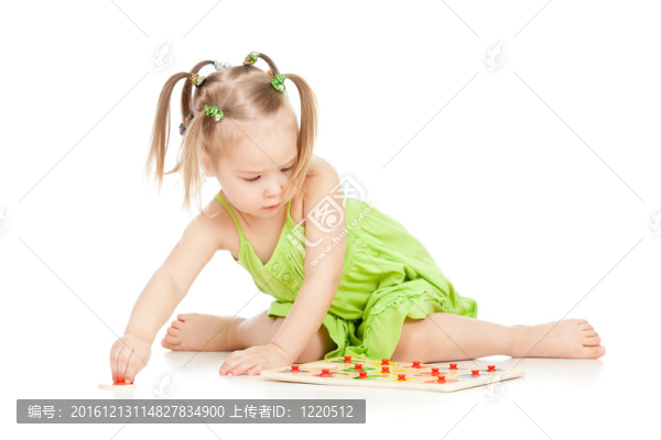 穿綠色連衣裙的小女孩在白地板上玩拼圖游戲