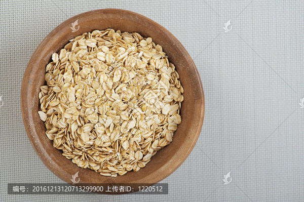 在一個(gè)灰色的布上用木碗軋制燕麥。
