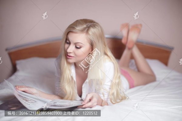 美麗性感性感金發(fā)女郎躺在床上看雜志