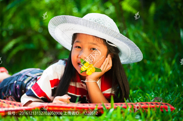 少女躺在草地上，頭上戴著一頂帽子，一朵花