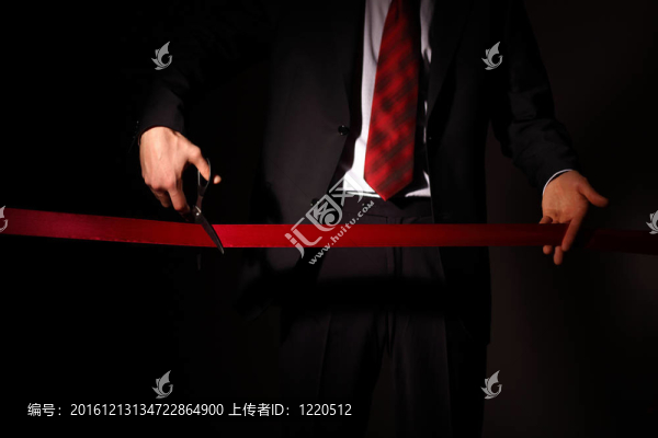 用剪刀切一個紅絲帶的商人