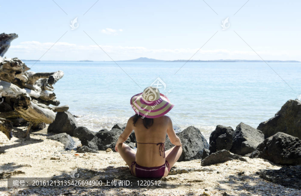坐在海灘上戴帽子的女人
