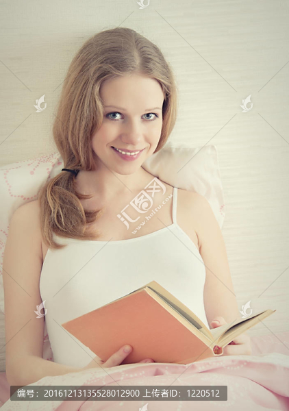 漂亮的金發(fā)女郎躺在床上看書