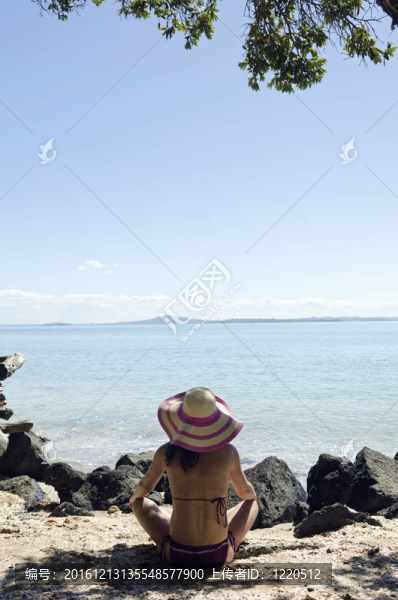 坐在海灘上戴帽子的女人