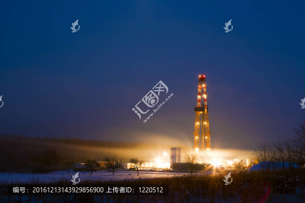 在下雪的風景中，油井在夜間點亮。