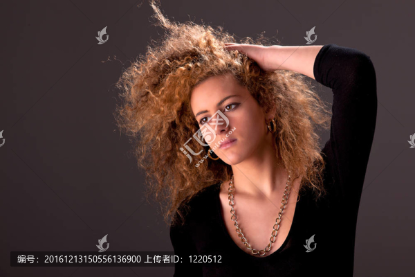 美麗的女人手拿著頭發(fā)；看相機；工作室拍攝