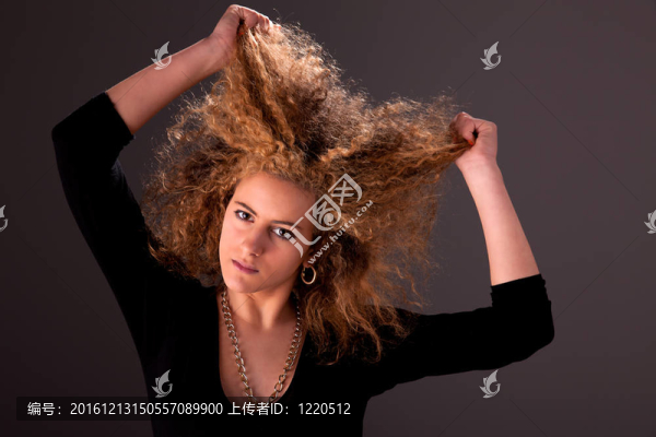 美麗的女人手拿著頭發(fā)；看相機(jī)；工作室拍攝