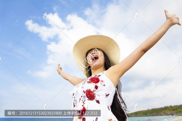 快樂的年輕女子在海灘上舉手