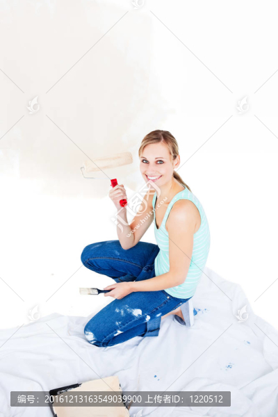 年輕的女人在新房子里畫一個房間