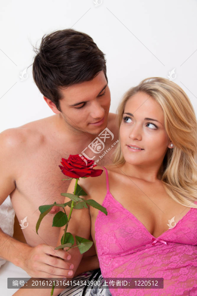 浪漫夫婦在床上與玫瑰。嫁給男人。