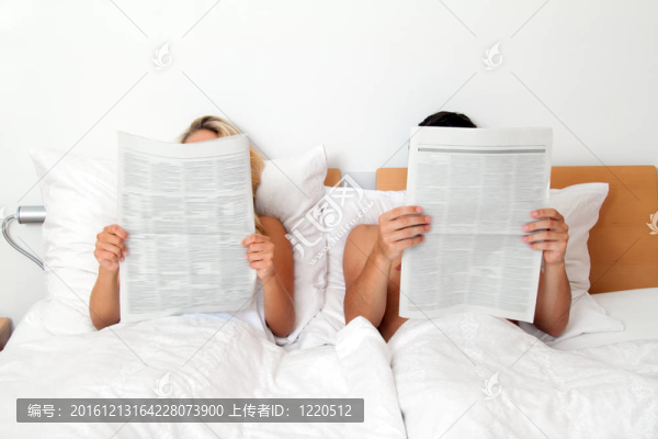 夫婦在床上看報紙。信息和新聞