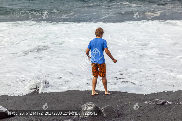 男孩在黑色火山海灘玩得開心