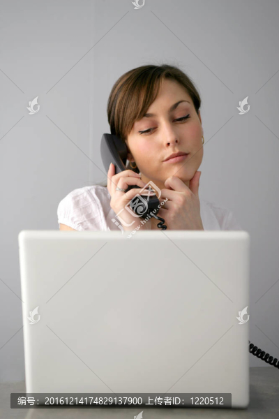 女人在電話里看著筆記本電腦