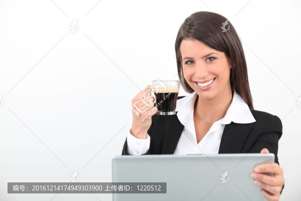 女人在筆記本電腦上喝咖啡