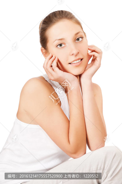 年輕漂亮的女人坐在地板上，撫摸著她那漂亮的臉孤立在白色背景