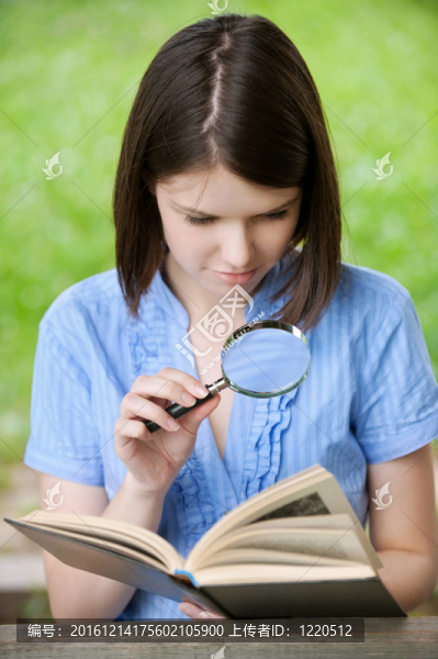 年輕的女人特寫閱讀放大鏡