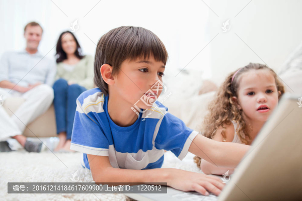 孩子們和他們的父母在地毯上玩電腦游戲