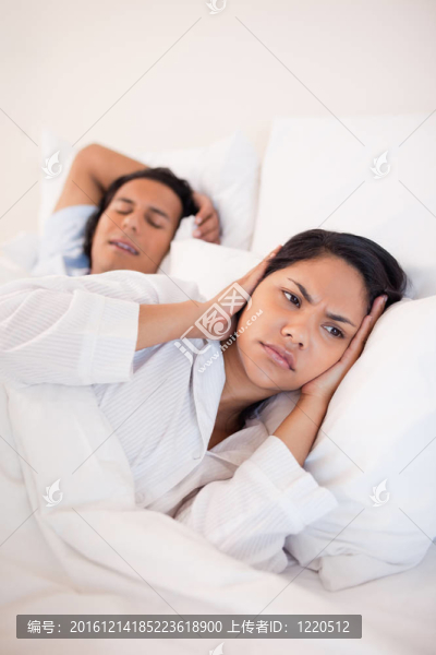 女人捂住耳朵擋住男友的鼾聲