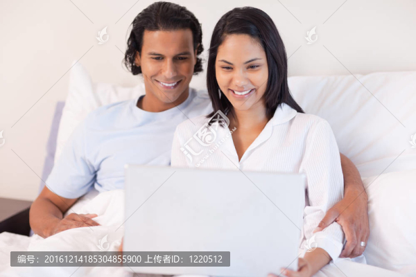 夫婦坐在床上與他們的筆記本電腦