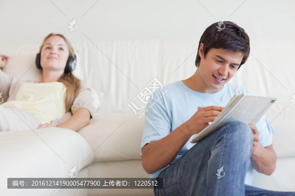 男人在做填字游戲，他的未婚妻是聽音樂