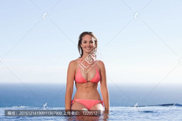微笑的女人坐在游泳池旁