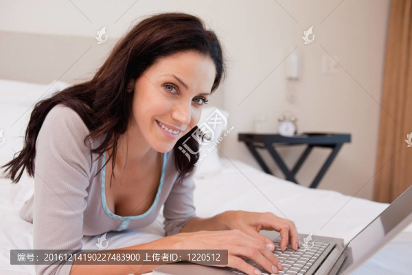 微笑的女人和她的筆記本電腦在床上