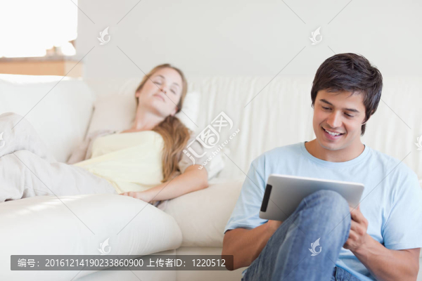 年輕人在他的女朋友睡在起居室時用平板電腦