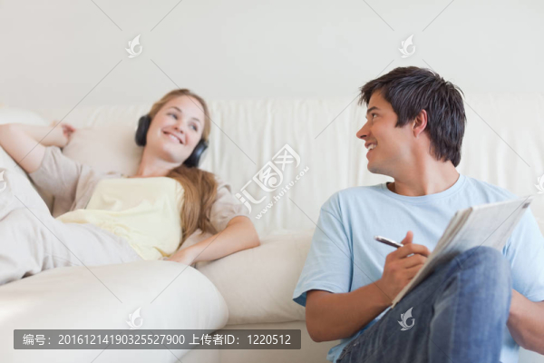 男人在做填字游戲，他的女朋友是聽音樂