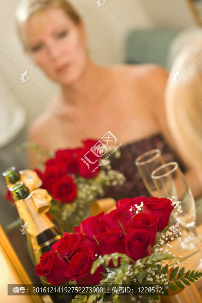 沉思的金發(fā)女郎坐在鏡子旁香檳和玫瑰