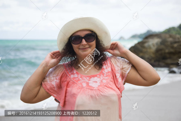 在海灘上戴著白帽子和太陽(yáng)鏡的女人