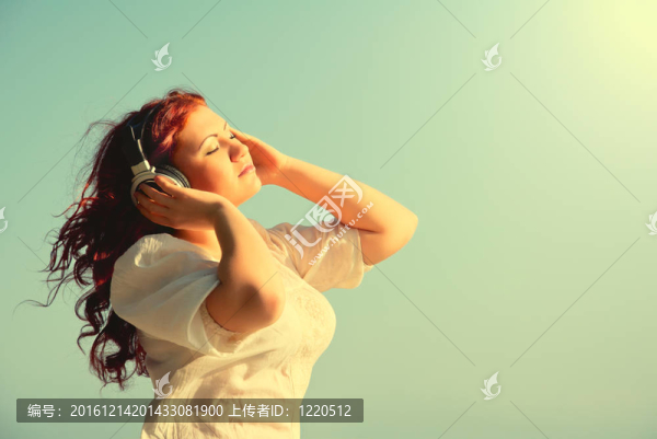 美麗的紅頭發(fā)的長頭發(fā)的女孩喜歡音樂headphon