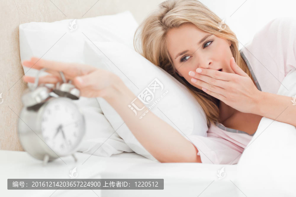 女人打哈欠，而她伸出沉默她的鬧鐘