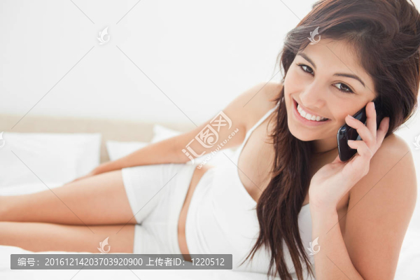 女人用智能手機，躺在床上微笑