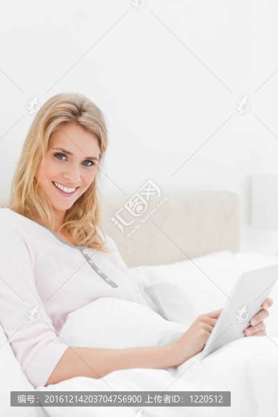 特寫鏡頭的一個微笑的女人誰是使用平板電腦，因為她正在尋找和有點到一邊。