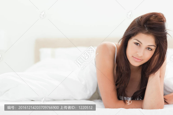 一個(gè)女人躺在床的右邊，一只胳膊放在她的頭上，另一只胳膊擱在床上。