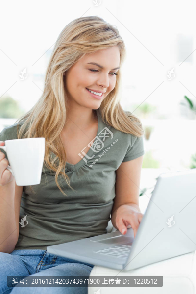 女人微笑；當(dāng)她用筆記本電腦拿著杯子