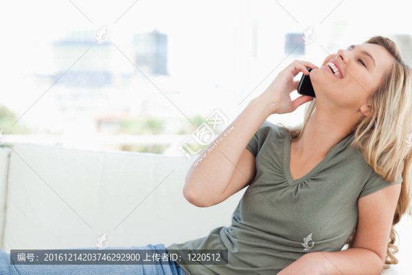 一個女人打電話，躺在沙發(fā)上，頭向后仰向上看。