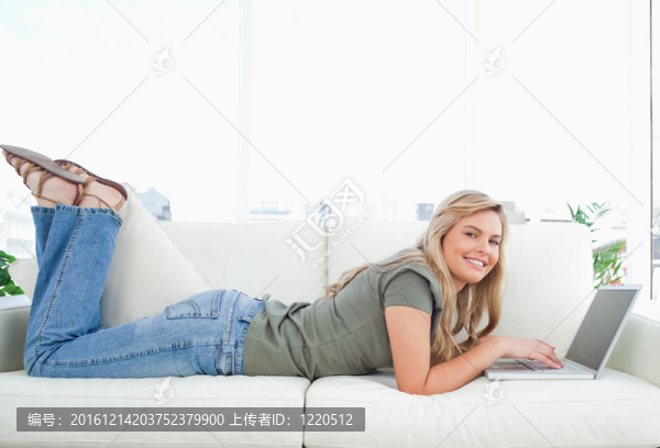一個(gè)女人用她的筆記本電腦，在她抬起腿的時(shí)候微笑著看著前方。