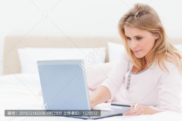 女人躺在床上用筆記本電腦；看著屏幕