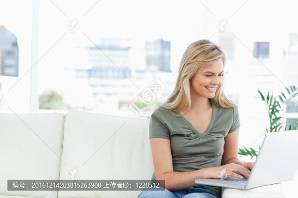 女人用筆記本電腦在沙發(fā)上微笑
