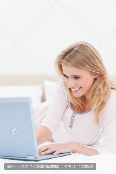 在床上微笑著用筆記本電腦的女人