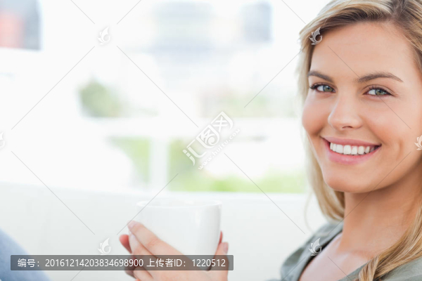 女人微笑著；向前看，手里拿著一只杯子