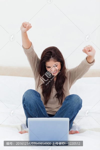 一個(gè)女人在空中抱著她的手臂；在床上看著她的筆記本。