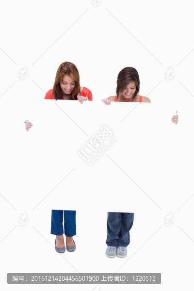 兩個十幾歲的女孩微笑著看著他們的空白海報