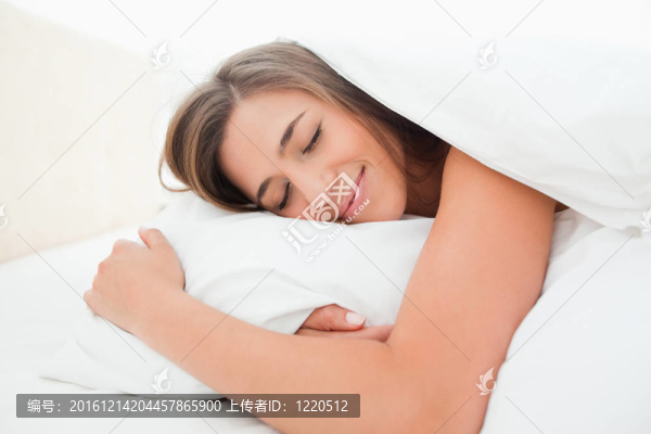女人睡在床上，面帶微笑，頭枕在枕頭上