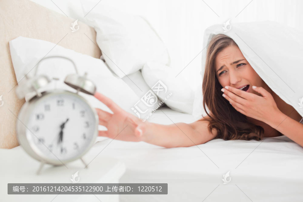 女人打哈欠而試圖壓制她的鬧鐘