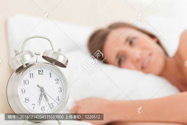 女人躺在床上，鬧鐘在她旁邊