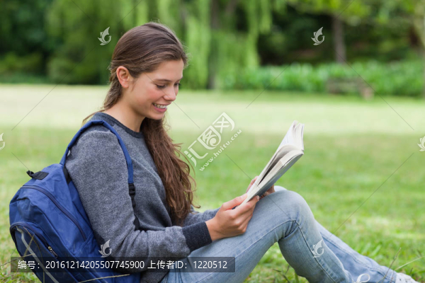 年輕輕松的女人坐在草地上看書